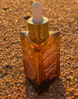 Amber glass dropper bottle with gold cap on a textured brown surface