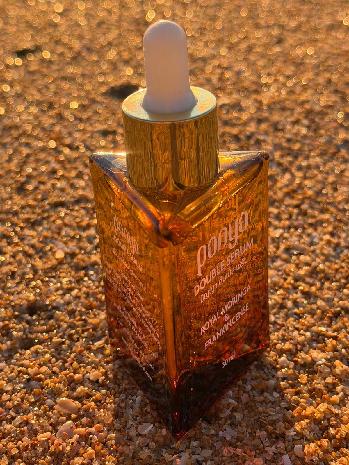Amber glass dropper bottle with gold cap on a textured brown surface